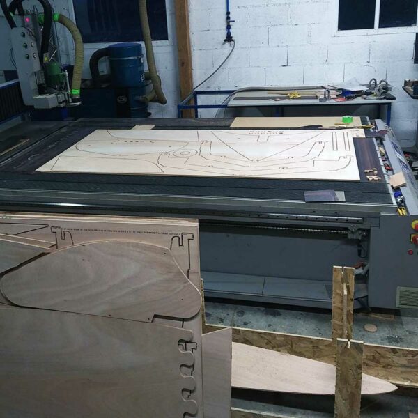 Fraiseuse CNC découpant des pièces en contreplaqué pour un bateau en kit.
