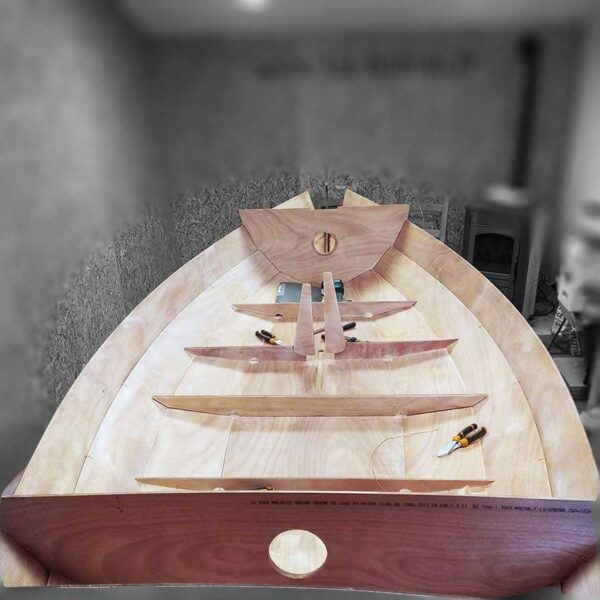 Étape d'assemblage de la structure interne d'un bateau en kit, montrant les membrures et les longerons en bois.